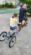 Young girl riding behind man on a Tandem Trailer Trike 