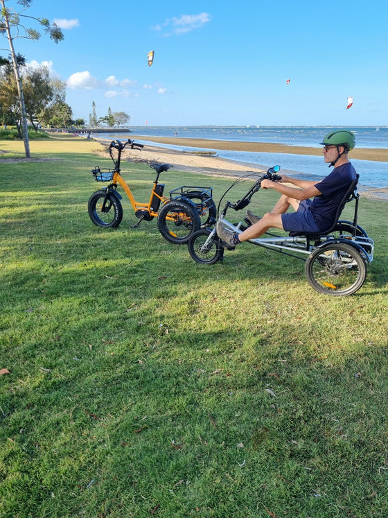 Man sitting on tricycle next to orange trike