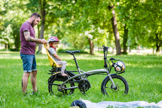 Man strapping child into her seat on the Tern Vektron S10 Electric Folding ebike