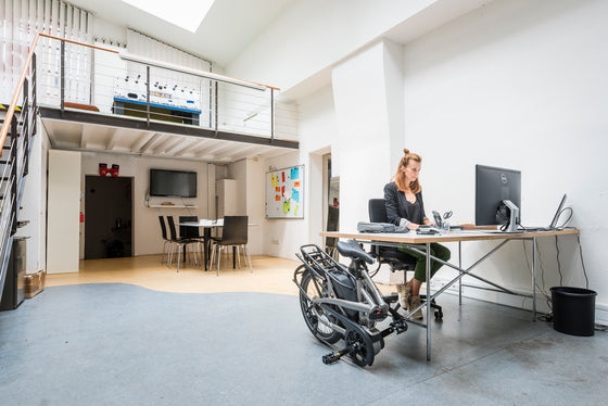 Women working at her desk with her folded Tern Vektron S10 Electric Folding ebike