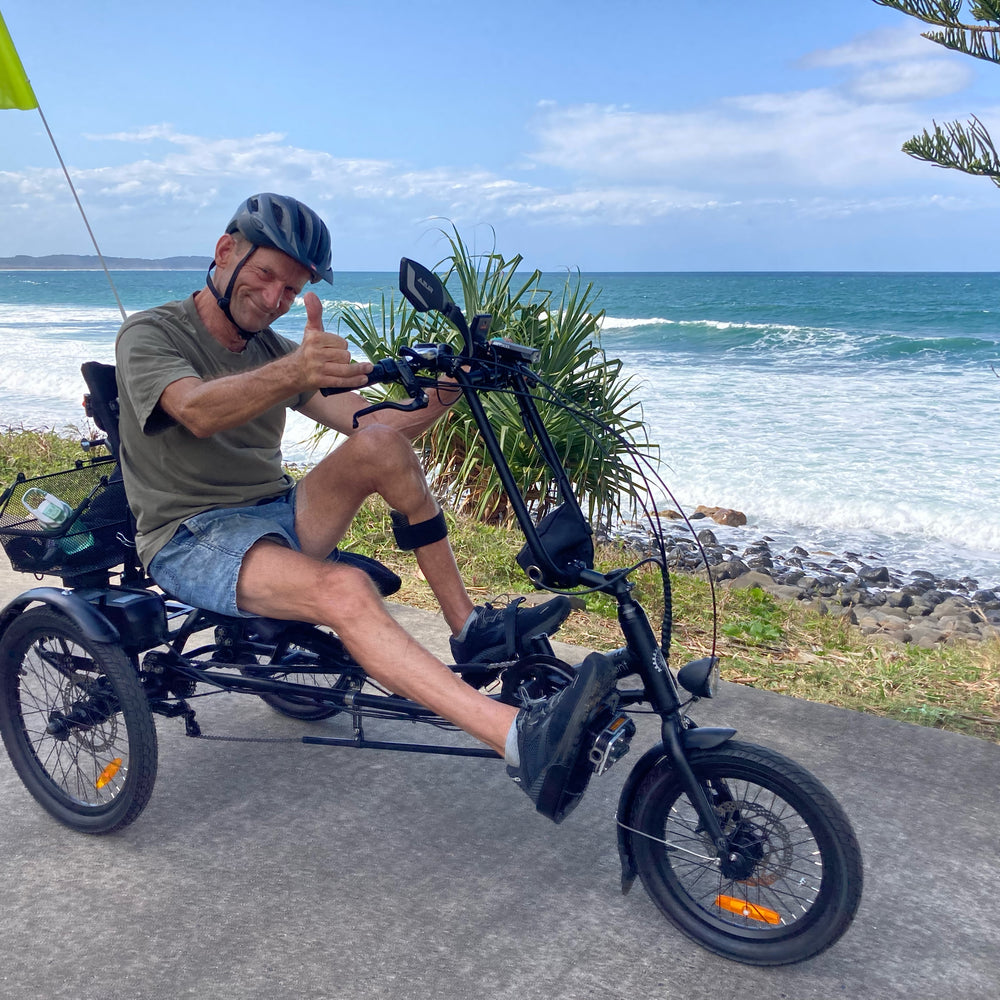 Roger riding a sit-down semi-recumbent tricycle after his stroke