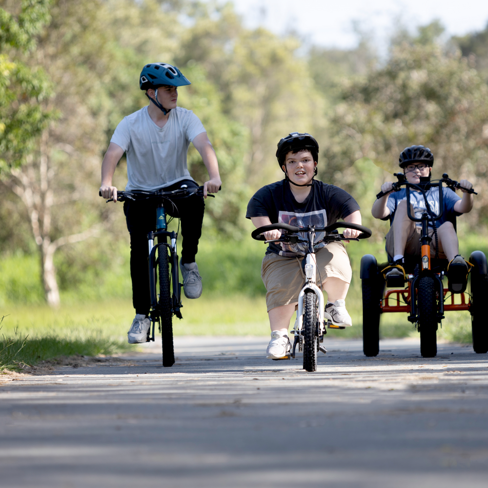 3 boys riding bikes together. LH rider on full sized bike, middle rider with short stature on Lightning ebike, right hand rider on sit-down electric Trident tricycle