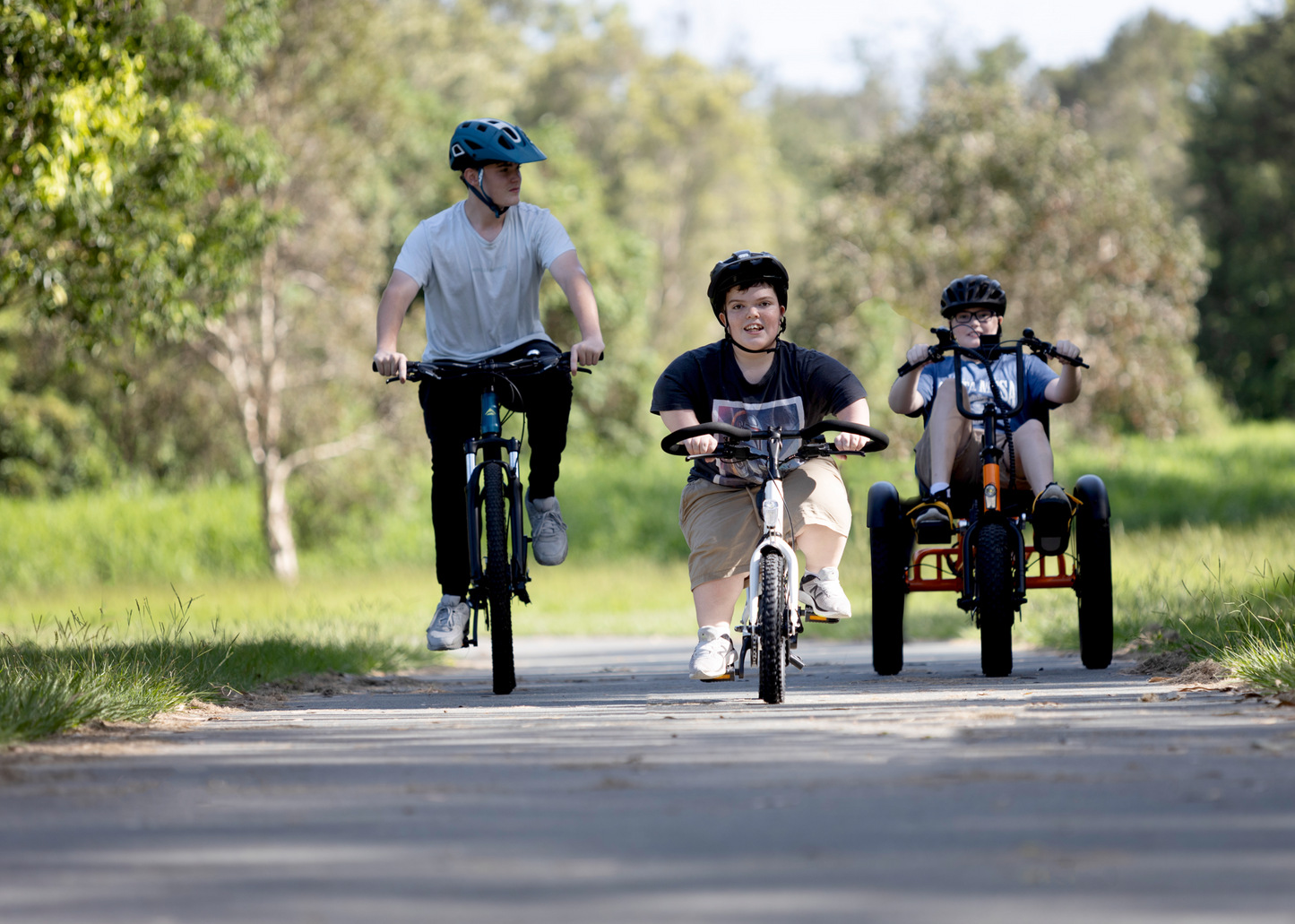 3 boys riding bikes together. LH rider on full sized bike, middle rider with short stature on Lightning ebike, right hand rider on sit-down electric Trident tricycle