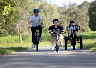  3 boys riding bikes together. LH rider on full sized bike, middle rider with short stature on Lightning ebike, right hand rider on sit-down electric Trident tricycle