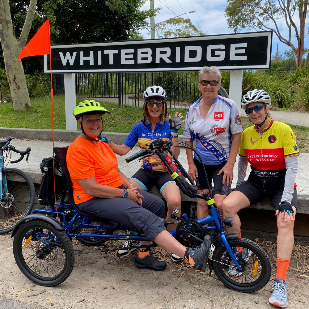 Women helping disabled man go for a bike ride