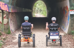  Two people riding on sit-down tricycles through a tunnel on a rail trail NRRT