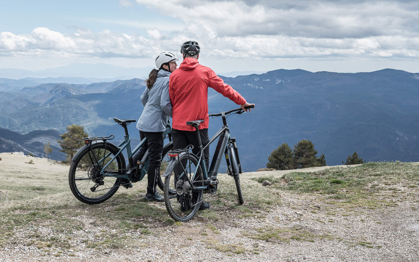 Two people riding mid-drive Kalkhoff electric bikes, standing overlooking mountains in the distance