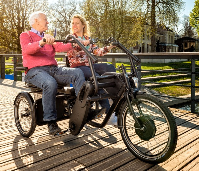 Two people sitting on a side-by-side Huka Orthros trike smiling and enjoying each others company