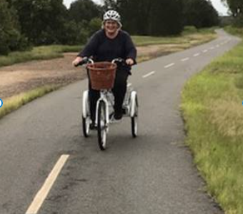 Lady riding a white upright electric tricycle along a bike path in Brisbane