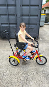 Smiling child while riding the Muskateer 14" tricycle with rear steer and special needs mods