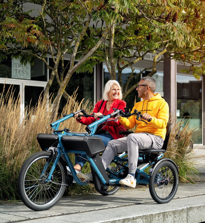 
                      
                        Lady and man smiling at eachother while riding the Huka Orthros Tandem Tricycle
                      
                    