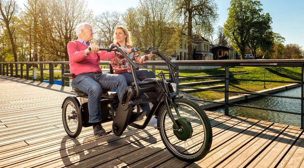 
                  
                    Older man looking at support person while riding on a Huka Orthros Tandem Tricycle
                  
                