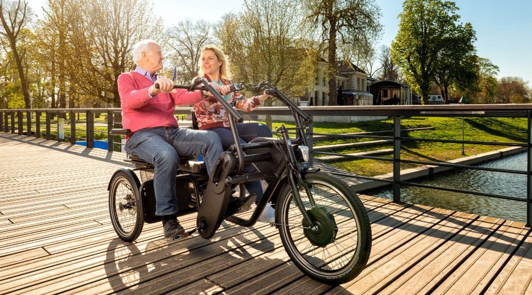 Older man looking at support person while riding on a Huka Orthros Tandem Tricycle