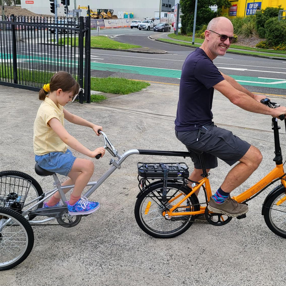 
                      
                        Younger girl riding on Tandem Trailer Trike with man at front
                      
                    