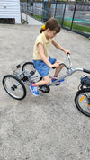 Young girl riding on the back of a Tandem Trailer Trike 