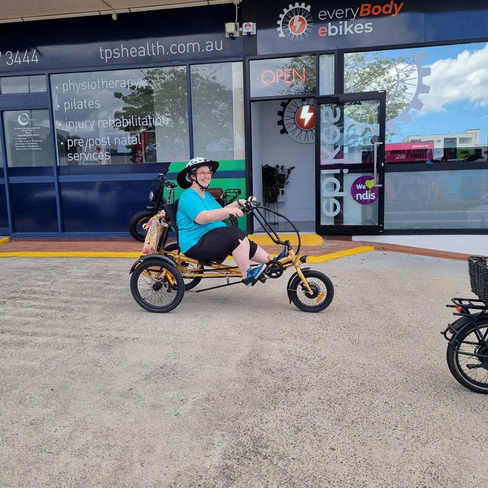 
                      
                        Happy customer outside everyBody ebikes riding a gold Trident semi-recumbent electric tricycle
                      
                    