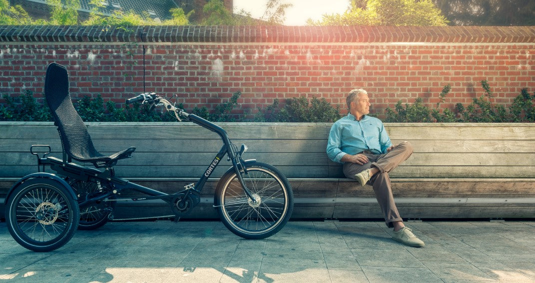 Man posing next to the Huka Cortes Electric Tricycle